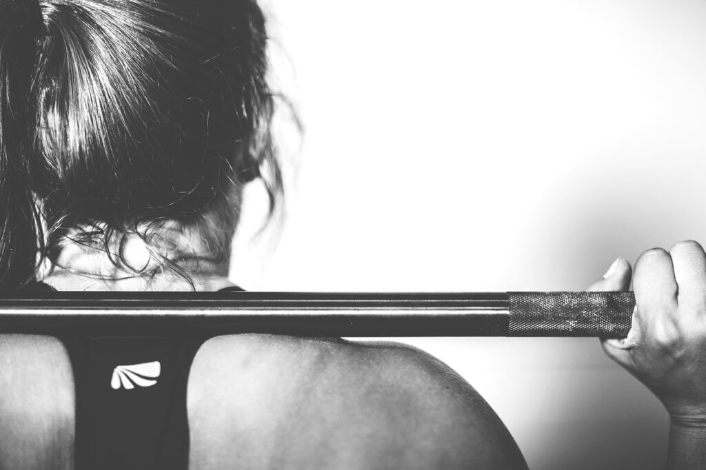 A woman performing a barbell squat exercise in a gym, demonstrating strength training for women for heart health and longevity