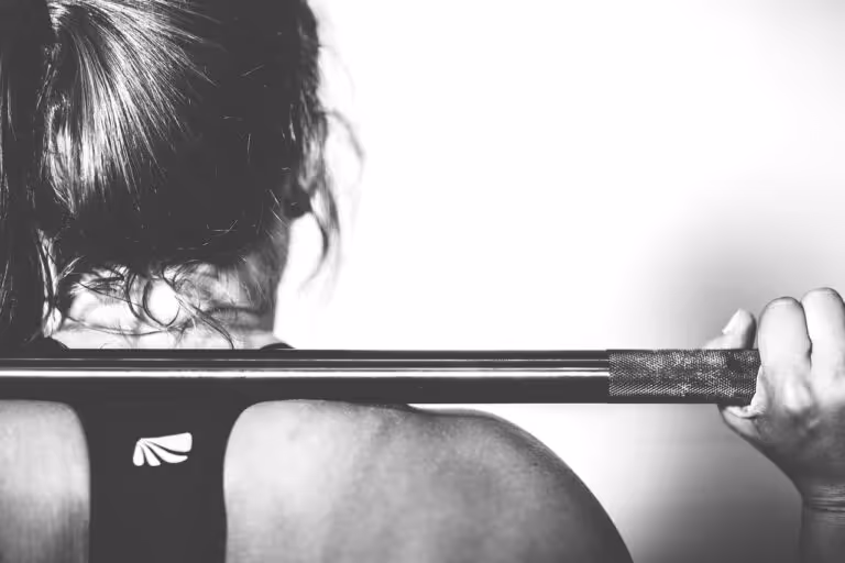 A woman performing a barbell squat exercise in a gym, demonstrating strength training for women for heart health and longevity