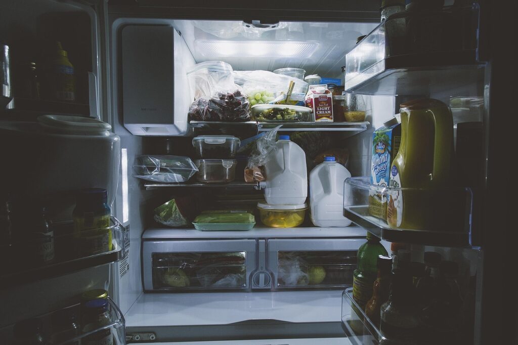 Glass bottles and food containers arranged on a refrigerator shelf, representing safe breast milk storage practices for breastfeeding mothers