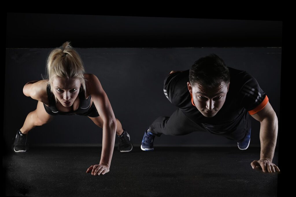 A woman and a man performing push-ups together on a fitness mat, representing strength training for muscle longevity and the three pillars of metabolic health, structural integrity, and cellular resilience.