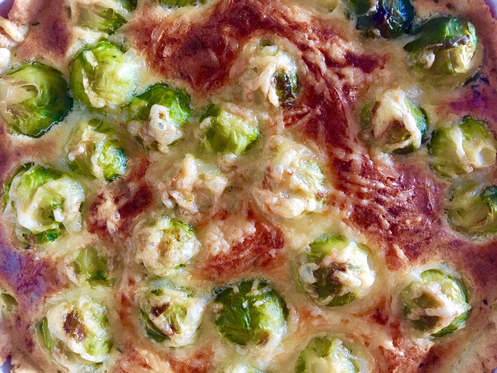 Close-up of a baked vegetarian casserole dish with roasted Brussels sprouts, melted cheese, and vegetables in a baking dish — perfect for a healthy weeknight dinner.