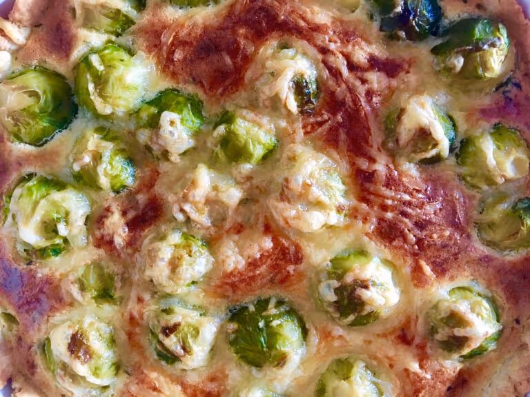 Close-up of a baked vegetarian casserole dish with roasted Brussels sprouts, melted cheese, and vegetables in a baking dish — perfect for a healthy weeknight dinner.