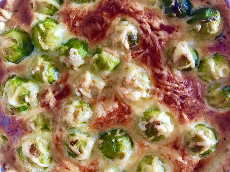 Close-up of a baked vegetarian casserole dish with roasted Brussels sprouts, melted cheese, and vegetables in a baking dish — perfect for a healthy weeknight dinner.