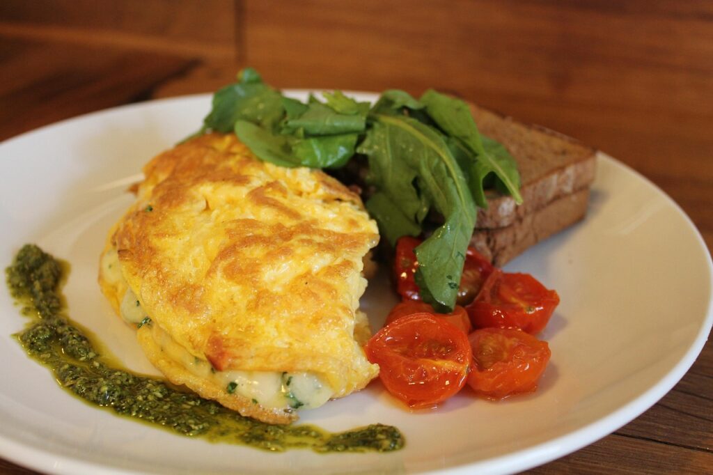 Healthy Mediterranean-style breakfast plate featuring an omelet with greens, grilled tomatoes, and whole-wheat toast on a rustic wooden table — representing a nutrient-dense meal that supports mitochondrial health