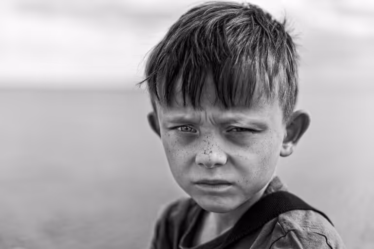 Black and white close-up portrait of a young boy with a thoughtful expression, representing the challenges and emotional complexity of boys mental health and the need for community support and mentorship.