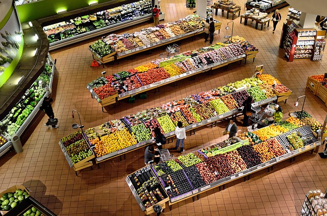 Brightly lit grocery store produce aisle with fresh fruits and vegetables on display, illustrating smart shopping for generic grocery foods to save money on healthy eating