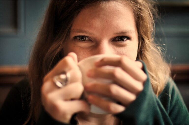 Woman smiling warmly while holding a cup of coffee, representing the heart health benefits of moderate coffee consumption supported by the American Heart Association