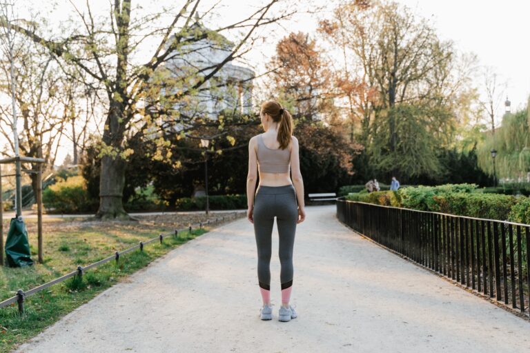 Woman in activewear walking along a sunlit park path after a meal to help manage blood sugar levels and support metabolic health