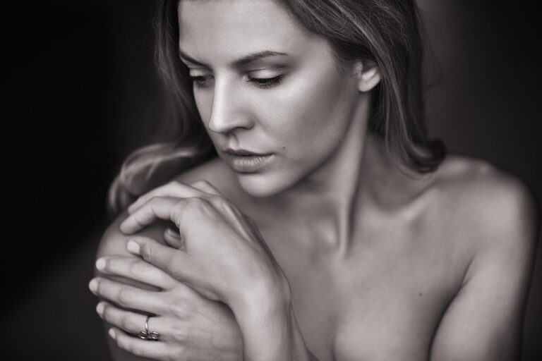 Woman gently touching her face near her chin, representing the relatable experience of managing PCOS facial hair with empathy and self-care