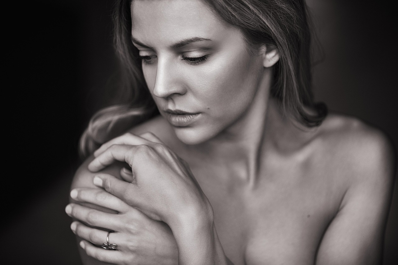 Woman gently touching her face near her chin, representing the relatable experience of managing PCOS facial hair with empathy and self-care