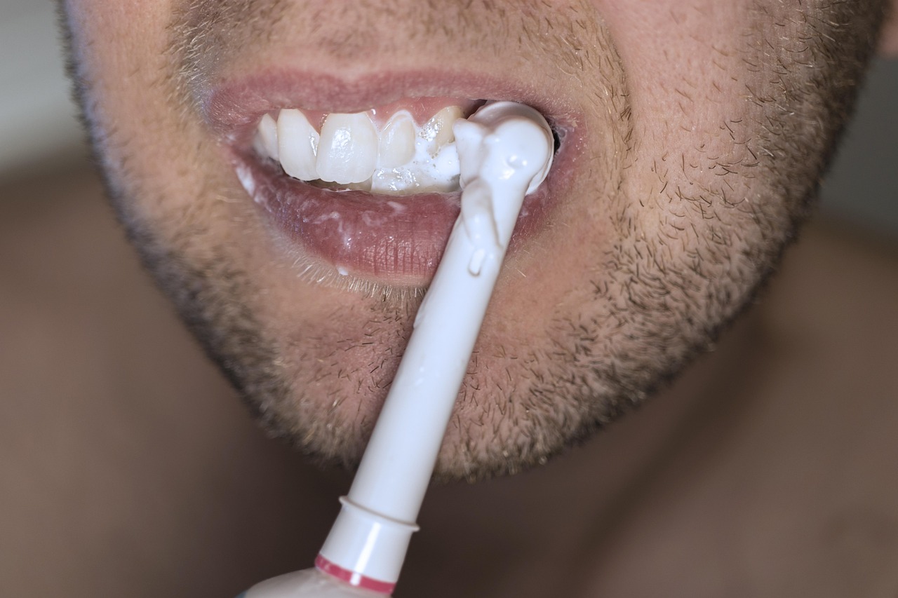 Closeup of a toothbrush with toothpaste, representing daily oral hygiene habits that support a healthy oral microbiome and whole-body wellness