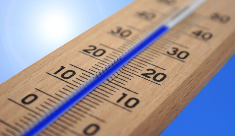 Outdoor thermometer showing high temperature against a bright sunny sky, representing extreme heat and heat wave conditions
