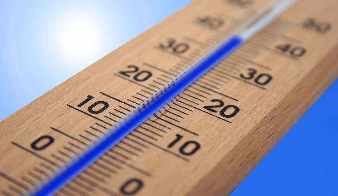 Outdoor thermometer showing high temperature against a bright sunny sky, representing extreme heat and heat wave conditions