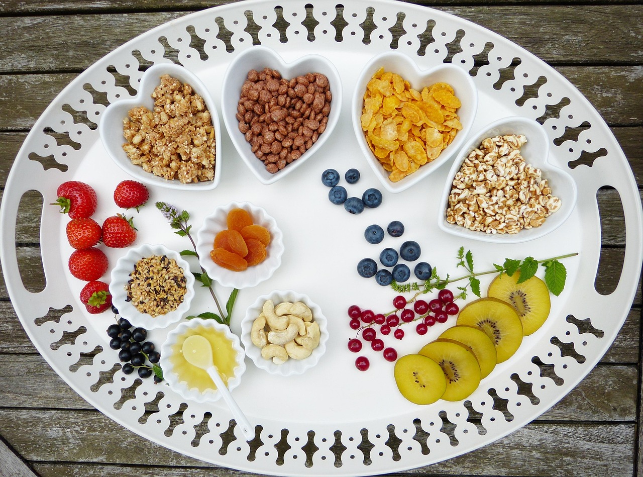 Flat lay of healthy diabetes-friendly breakfast bowls with muesli, fresh fruits like berries and bananas, displayed on a wooden tray - ideal for blood sugar friendly morning meals