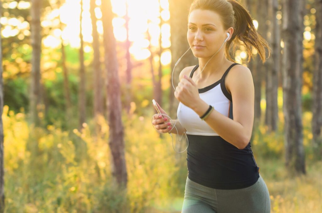 Young woman jogging outdoors with earphones, representing an active healthy lifestyle for PCOS weight loss management