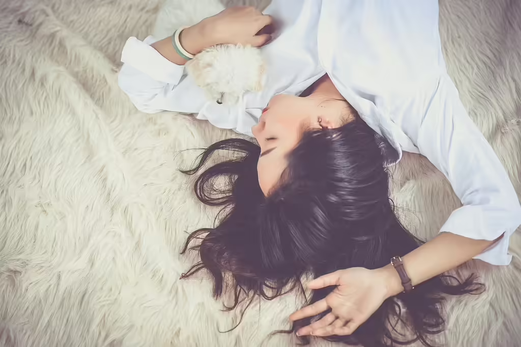 Young woman resting peacefully asleep on a bed with her dog, representing the calming and sleep-promoting benefits of magnesium glycinate supplementation