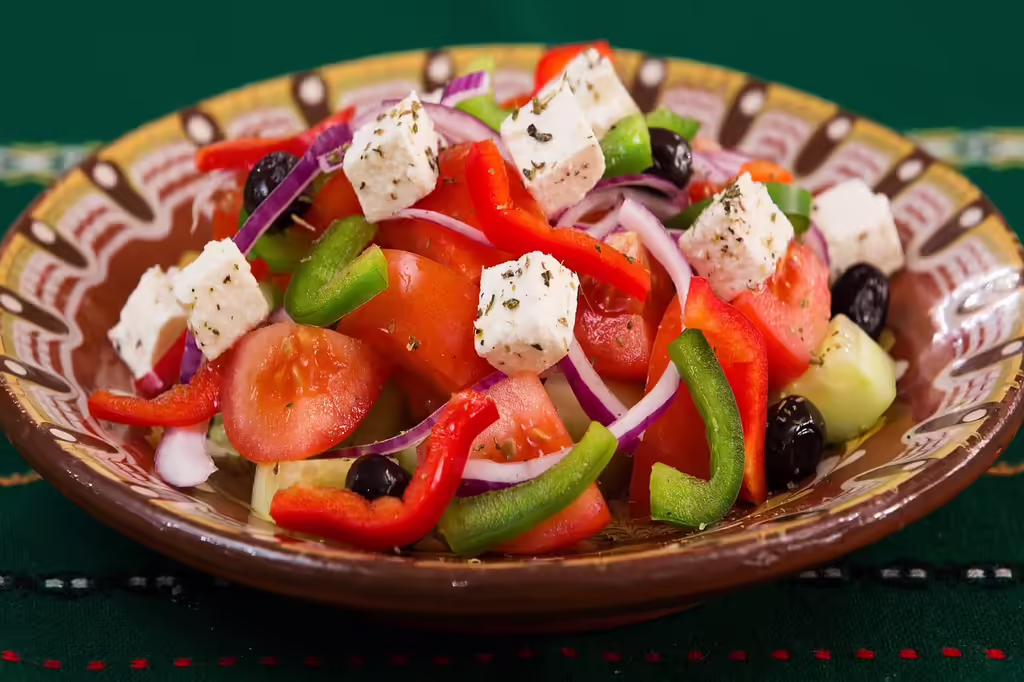Fresh Mediterranean Greek salad with feta cheese, tomatoes, cucumbers, olives, and peppers on a wooden table - perfect pairing for feta brined chicken bowls