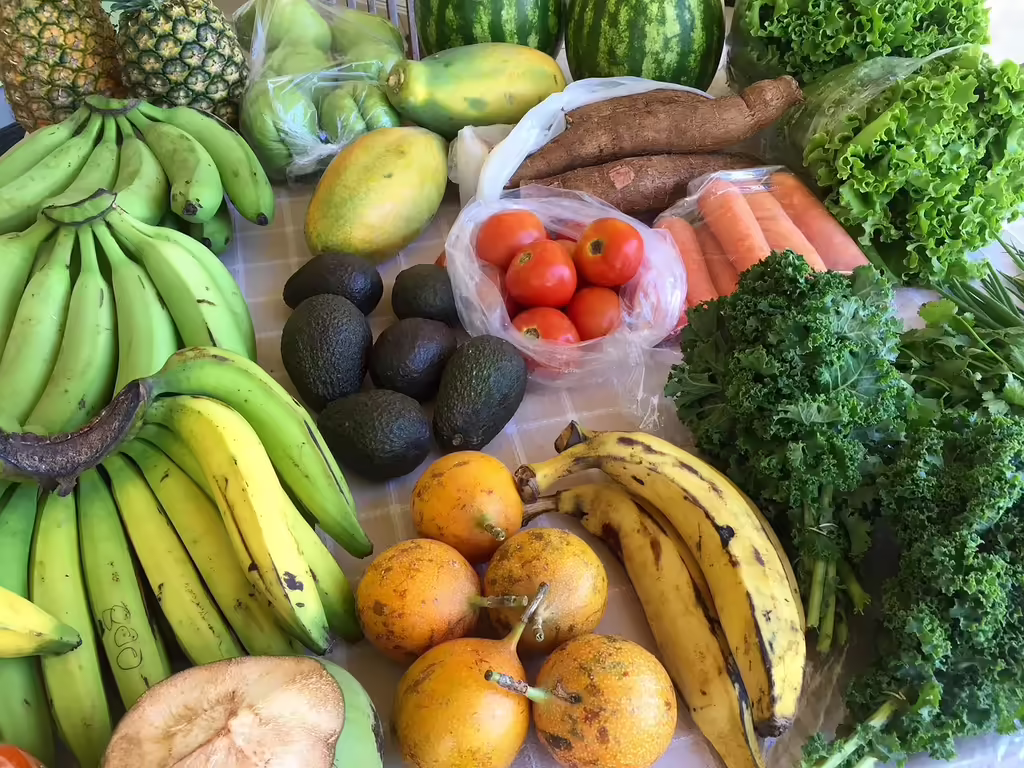 Vibrant assortment of fresh fruits and vegetables including leafy greens, avocados, bananas, and pineapples at a farmer's market - ideal for an anti-inflammatory diet rich in colorful produce