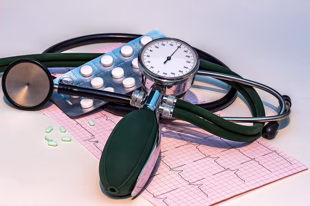 Blood pressure monitor, stethoscope, and ECG heart rhythm chart on a table with medication, representing tools for monitoring evening blood pressure and hypertension management